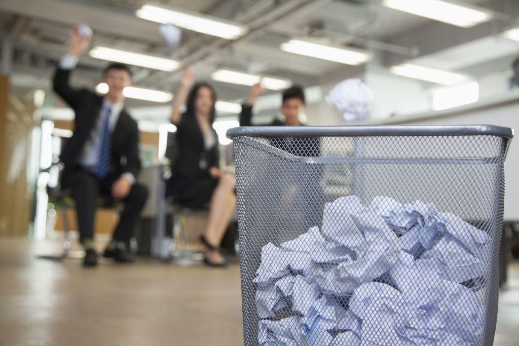 Employees throwing paper into a bin
